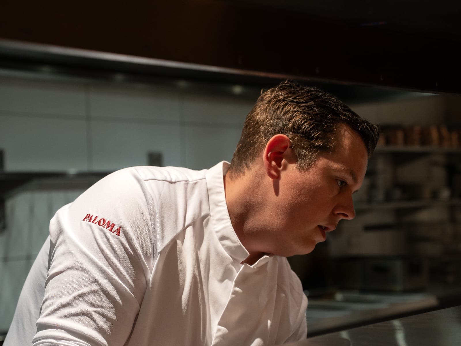 Chef en veste blanche avec le logo de son restaurant brodé sur la manche