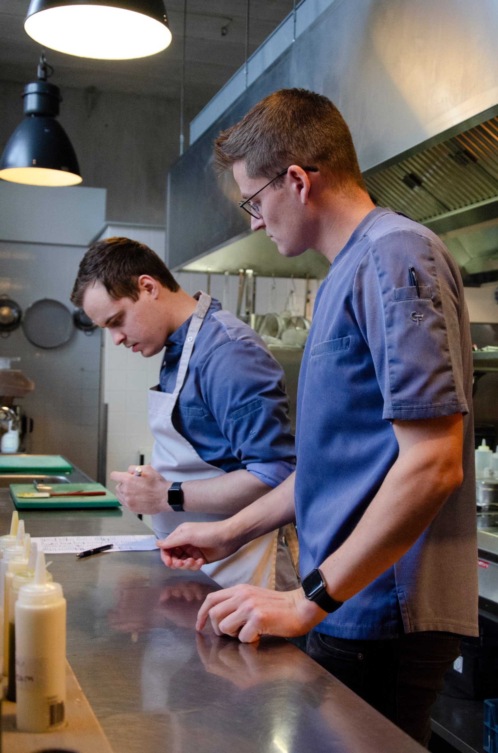 Zwei Köche in blauen Wastewear-Kochjacken an der Arbeitsfläche in einer Profiküche